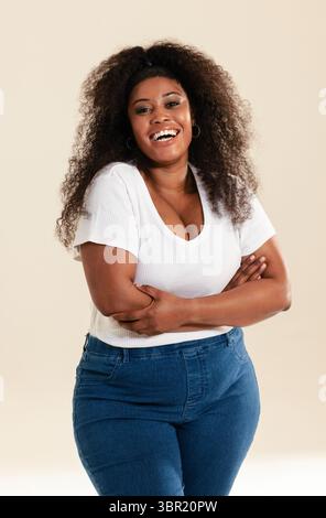 African American woman smiling and posing in studio wearing gold hoop earrings and necklace. Portrait, confidence, happiness, casual, beauty, elegance Stock Photo