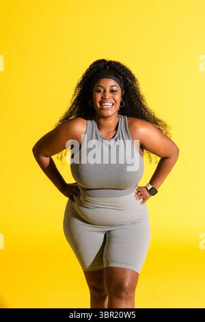 African American woman posing in studio wearing athletic wear, smartwatch, hoop earrings, headband. Fitness, wellness, activewear, lifestyle, motivati Stock Photo