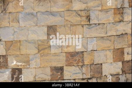 Close-up texture of stacked stone wall blocks in outdoor setting. Stock Photo