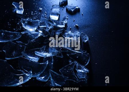 Broken Glass Shards on Dark Surface with Cold Lighting Stock Photo