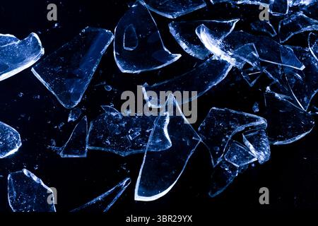 Broken Glass Shards on Dark Surface with Cold Lighting Stock Photo