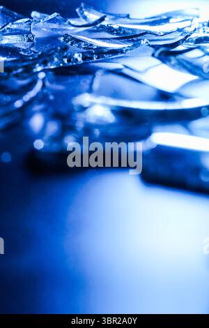 Broken Glass Shards on Dark Surface with Cold Blue Lighting Stock Photo