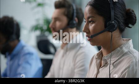 Close up smiling multiethnic team group operators diverse callcenter workers headset microphone consulting customer online service sales Indian Stock Photo