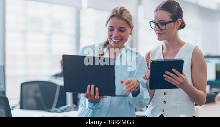 Women Engaging in Collaborative Efforts on Digital Devices within a Contemporary Office Environment Stock Photo