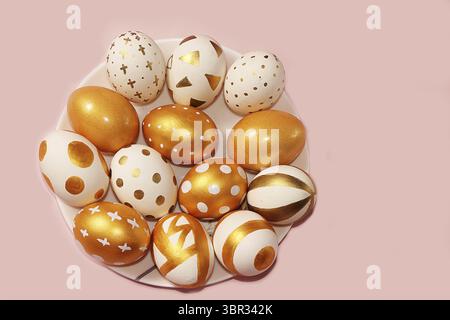 Decorated golden easter eggs on a pink background. Minimal holiday concept. Happy easter background. Creative painting of eggs at home Stock Photo