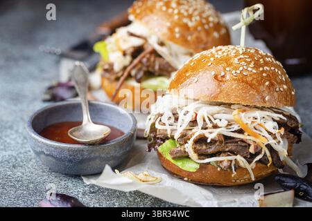 Pulled beef burger with cabbage salad and bbq sauce on paper Stock Photo