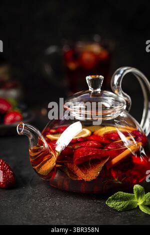 Fruit red tea with berries in glass teapot on black background Stock Photo