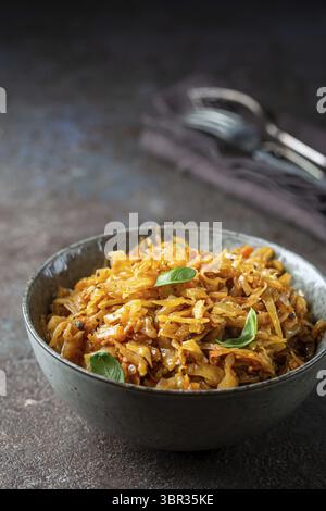 Stewed or braised cabbage served in a bowl on dark stone background, close up Stock Photo