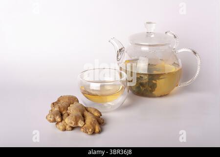 Glass teapot with green tea, cup, ginger on a white background Stock Photo