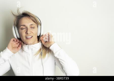 Portrait of smiling pretty woman enjoying music with white headphones on white background Stock Photo