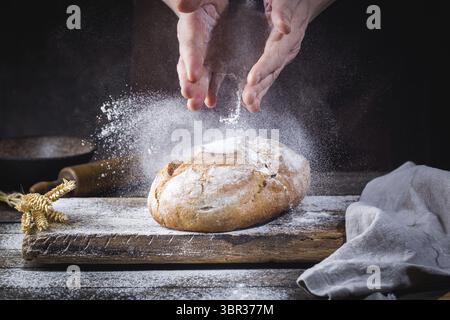 Baker cooking bread. Man slaps flour over the dough. Man's hands Making bread Stock Photo