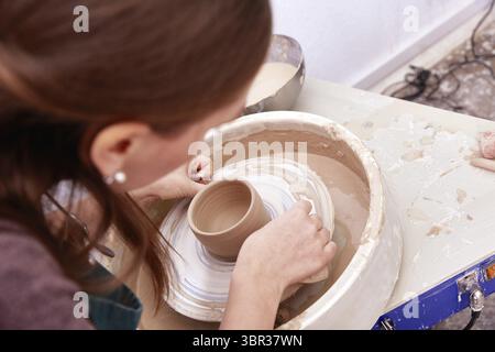 Faceless woman makes dishes on a potter's wheel Stock Photo