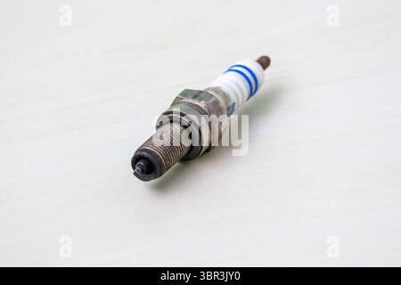 Dirty used motorcycle spark plug clearly showing black carbon deposits on the electrode. Indicating a need for service, repair, or immediate replaceme Stock Photo