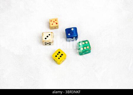Many colorful Ludo game dice isolated on a white background. Various old plastic Ludo dice with different numbers are scattered. Stock Photo