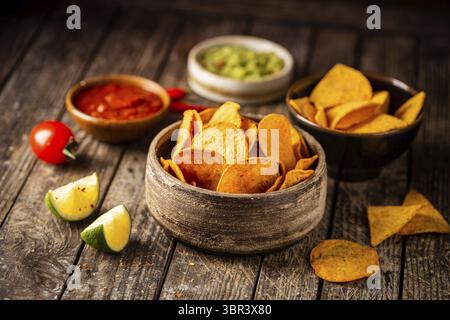 Two biowls of yellow corn tortilla nachos chips with salsa and guacamole sauce over wooden background Stock Photo