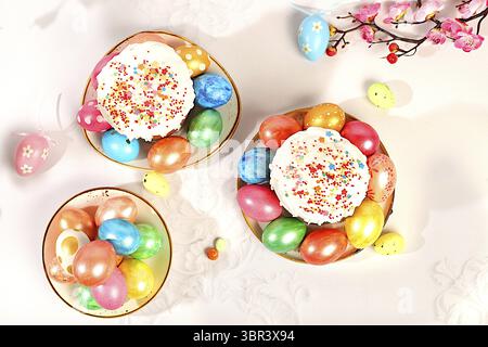Abstract Easter composition with traditional Russian kulich with meringue and decorated eggs on elegant kitchen table with spring sakura flowers. Happ Stock Photo