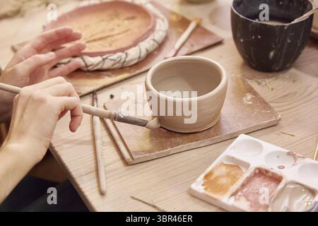 Faceless woman paints a clay bowl. close up Stock Photo