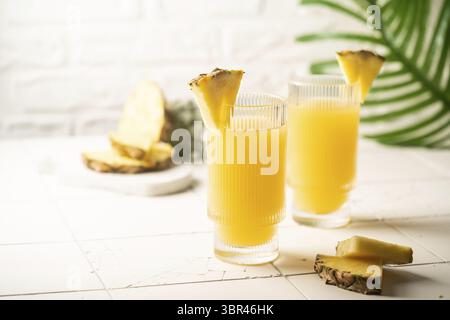 Pineapple cocktail or juice in two glasses with ice on white background with palm leaves Stock Photo
