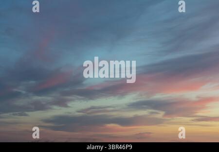 Vibrant twilight colors blend in the sky above a peaceful landscape during sunset showcasing soft clouds and a tranquil atmosphere that inspires calm. Stock Photo
