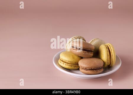 Colored macaroons in a plate on a beige background, copy space Stock Photo