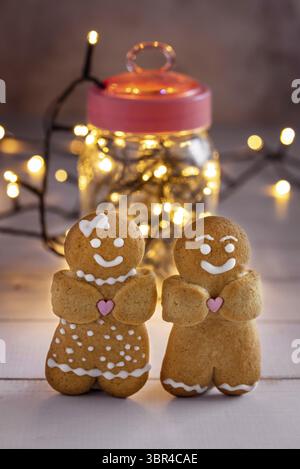 Two gingerbread men on the background of a jar with garlands. Vertical shot Stock Photo