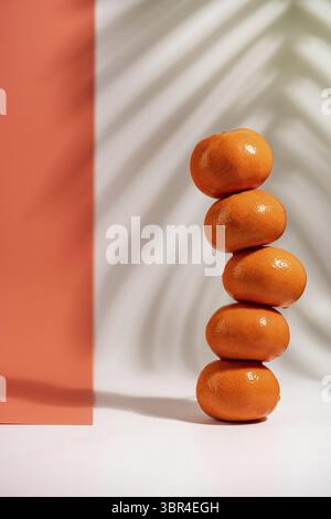 Stacked tangerines isolated on white and orange background. Healthy eating. Minimalism and balance concept with bright shadows Stock Photo