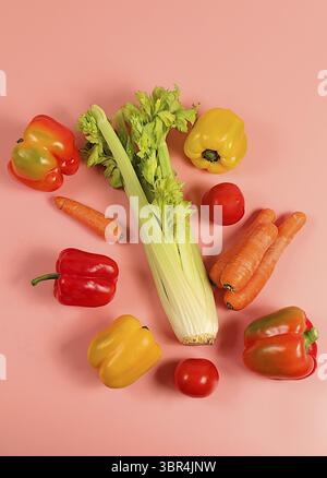 Sweet bell peppers, tomatoes, celery and carrots on a light table. Modern still life of various ripe vegetables for healthy vegetarian food and detox Stock Photo