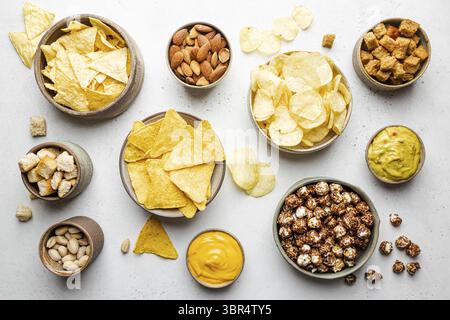 Veraity bowls of beer snacks and sauces on stone table. Nuts, chips, nachos, crackers. Top view with copyspace Stock Photo