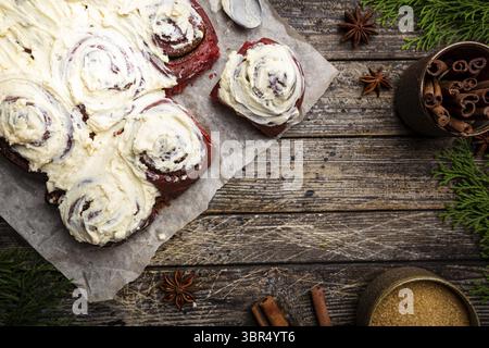 Homemade cinnamon rolls red velvet with cream cheese glaze on wooden background, top view Stock Photo