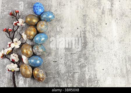 Happy Easter concept. Abstract Easter composition with marbled blue-gray decorated eggs, and flowering branches with sakura flowers, painted with hibi Stock Photo