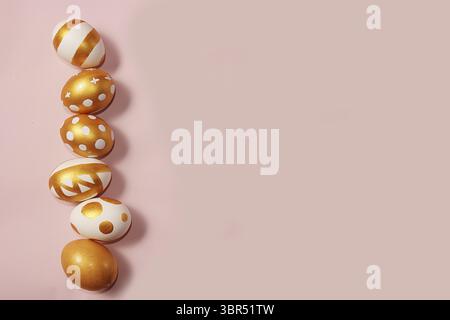 Decorated golden easter eggs on a pink background. Minimal holiday concept. Happy easter background. Creative painting of eggs at home Stock Photo