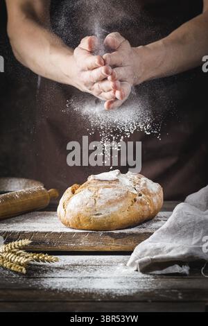 Baker cooking bread. Man slaps flour over the dough. Man's hands Making bread Stock Photo