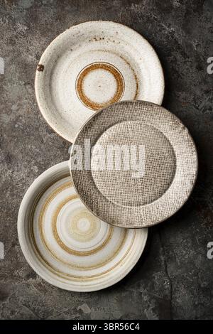 Three different homemade ceramic plates on dark gray background, top view Stock Photo