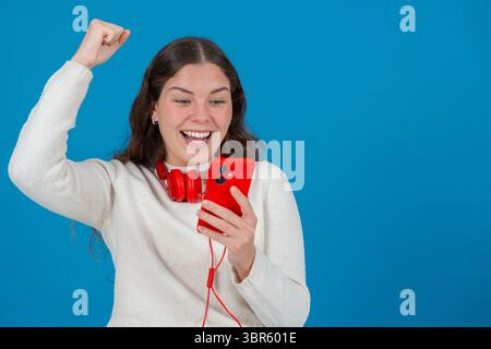 Excited Young Woman Celebrating While Looking at Smartphone Stock Photo