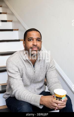 Contemplative man with coffee relaxes on vintage staircase Stock Photo