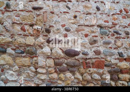 An old stone wall made of pebbles and bricks. Texture. Architecture. Stock Photo