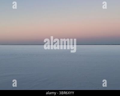 The beautiful pastel sky meets a tranquil, reflective water surface at dusk or dawn. Stock Photo