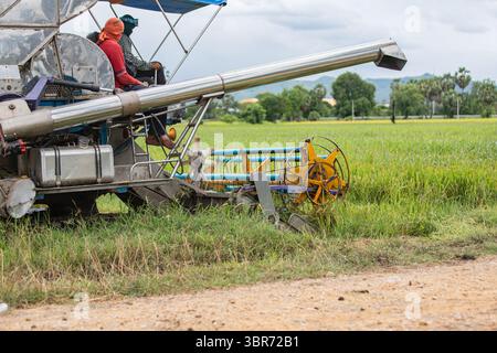 Workers on rice harvester in Thai countryside Stock Photo