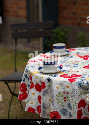 Tea Cups On A Floral Tablecloth In The Garden Stock Photo
