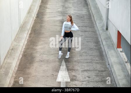 Confident Woman Posing in Athletic Wear on Urban Street Stock Photo