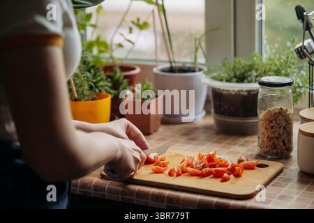 Woman slicing cherry tomatoes on cutting board Stock Photo
