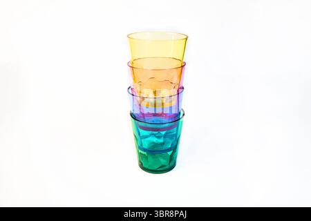 Stacked clear plastic cups in yellow, pink, blue, and green on a white background. Colourful transparent drinkware arranged in a neat vertical stack. Stock Photo