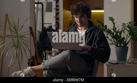 Focused Hispanic guy hipster user holding laptop purchasing delivery at home freelancer developer type man trader search information online Internet Stock Photo