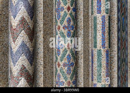 Geometric Mosaic Patterns at National Zoo Reptile Discovery Center in Washington DC | WASHINGTON D.C., United States — Chevrons and diamond lattices in red, blue, and green stone pick out the columns framing the Reptile Discovery Center's entrance at the National Zoo, part of John Joseph Earley's 1931 polychrome concrete ensemble. Earley achieved the color by embedding crushed stone and glass aggregate into white Portland cement, then exposing it before the surface fully cured. The roughly 25-foot (7.6-meter) portico was later dismantled and moved into storage after engineers found structural  Stock Photo