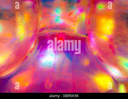 A vibrant, abstract artwork featuring a close-up of a shiny, surface reflecting multicolored light. The dominant hues are red, orange, yellow, and pin Stock Photo