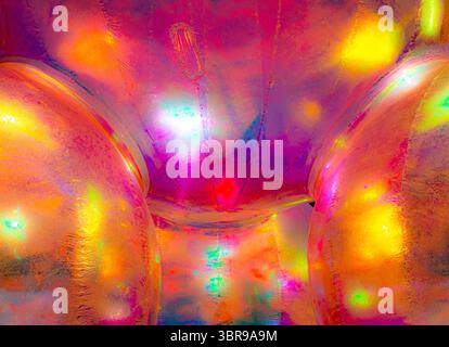 A vibrant, abstract artwork featuring a close-up of a shiny, surface reflecting multicolored light. The dominant hues are red, orange, yellow, and pin Stock Photo