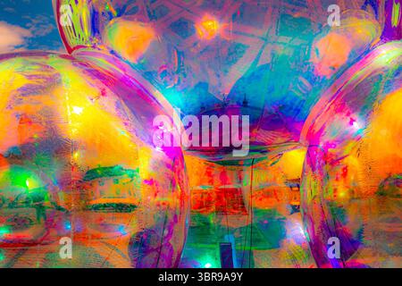 A vibrant, abstract artwork featuring a close-up of a shiny, surface reflecting multicolored light. The dominant hues are red, orange, yellow, and pin Stock Photo