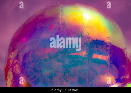 A vibrant, abstract artwork featuring a close-up of a shiny, surface reflecting multicolored light. The dominant hues are red, orange, yellow, and pin Stock Photo
