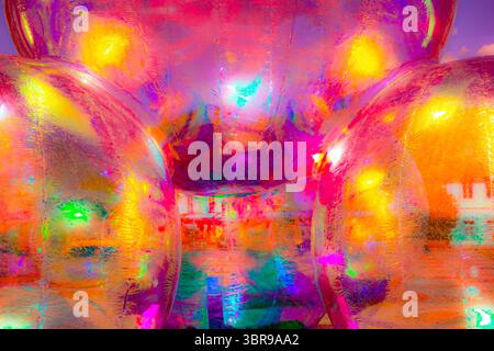 A vibrant, abstract artwork featuring a close-up of a shiny, surface reflecting multicolored light. The dominant hues are red, orange, yellow, and pin Stock Photo