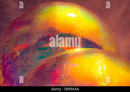 A vibrant, abstract artwork featuring a close-up of a shiny, surface reflecting multicolored light. The dominant hues are red, orange, yellow, and pin Stock Photo